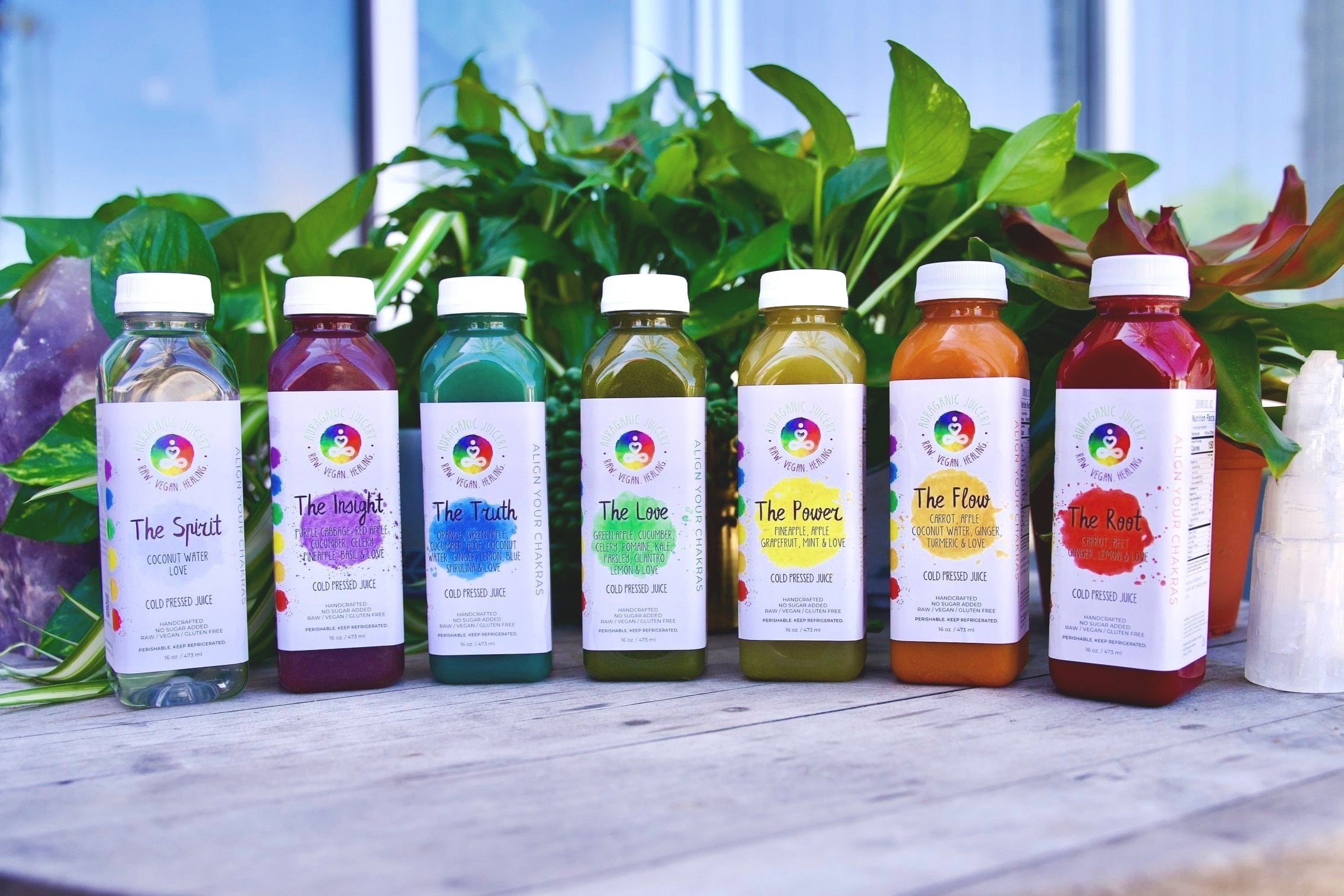 A close-up shot of a Auraganic Juicery's Chakra Juice cleanse bottles with vibrant colorful hues of the juice inside, showcasing it's health benefits.